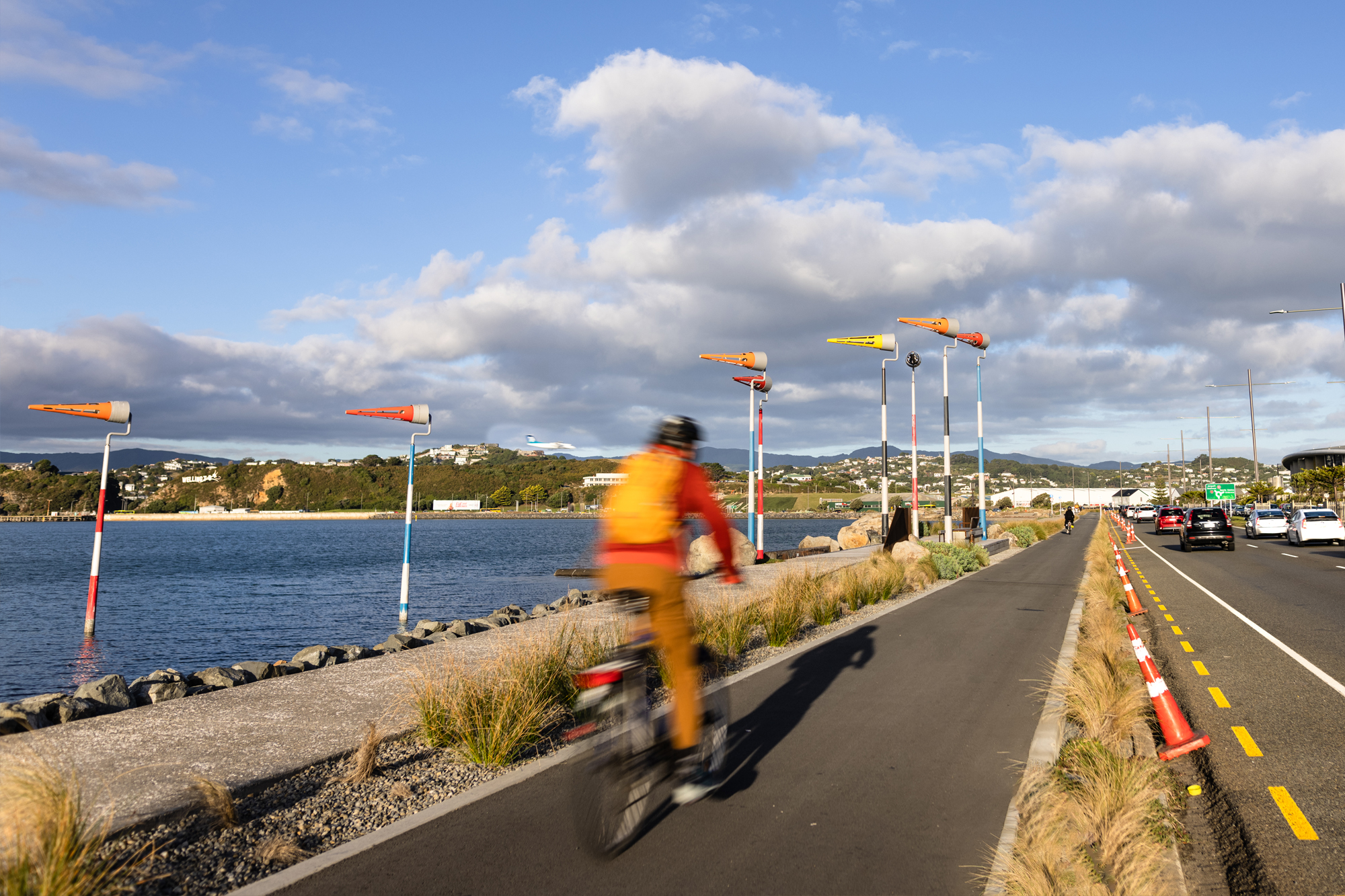Cyclist on shared path with road to the right and Evans Bay to the left
