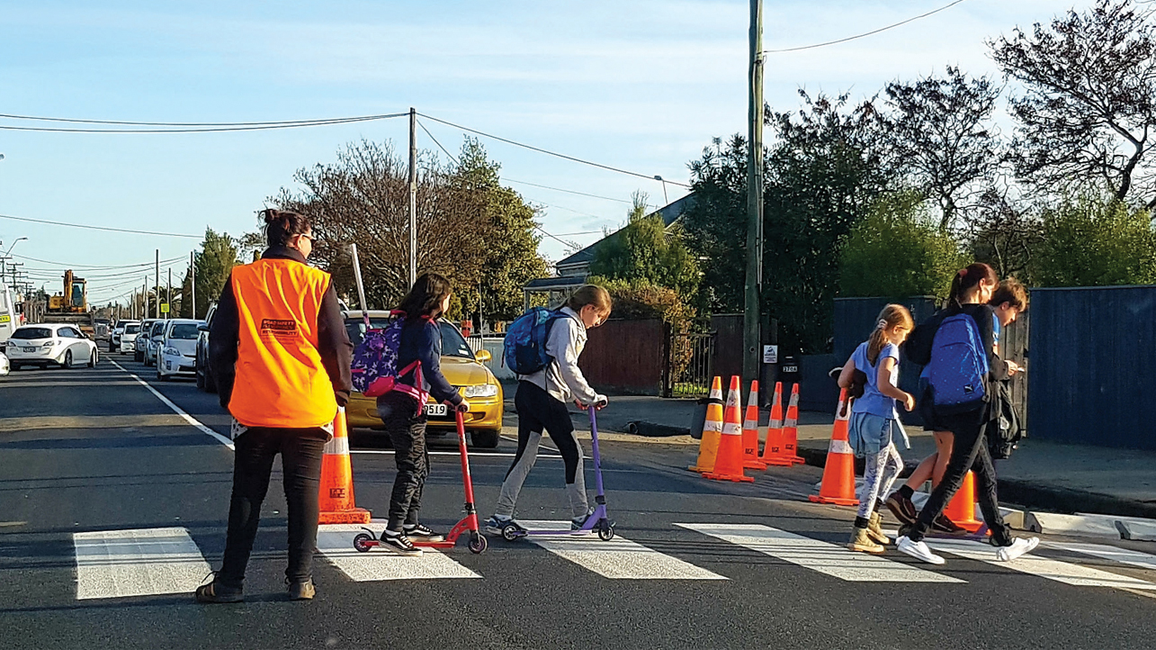 Children walking their scooters across a pedestrian crossing