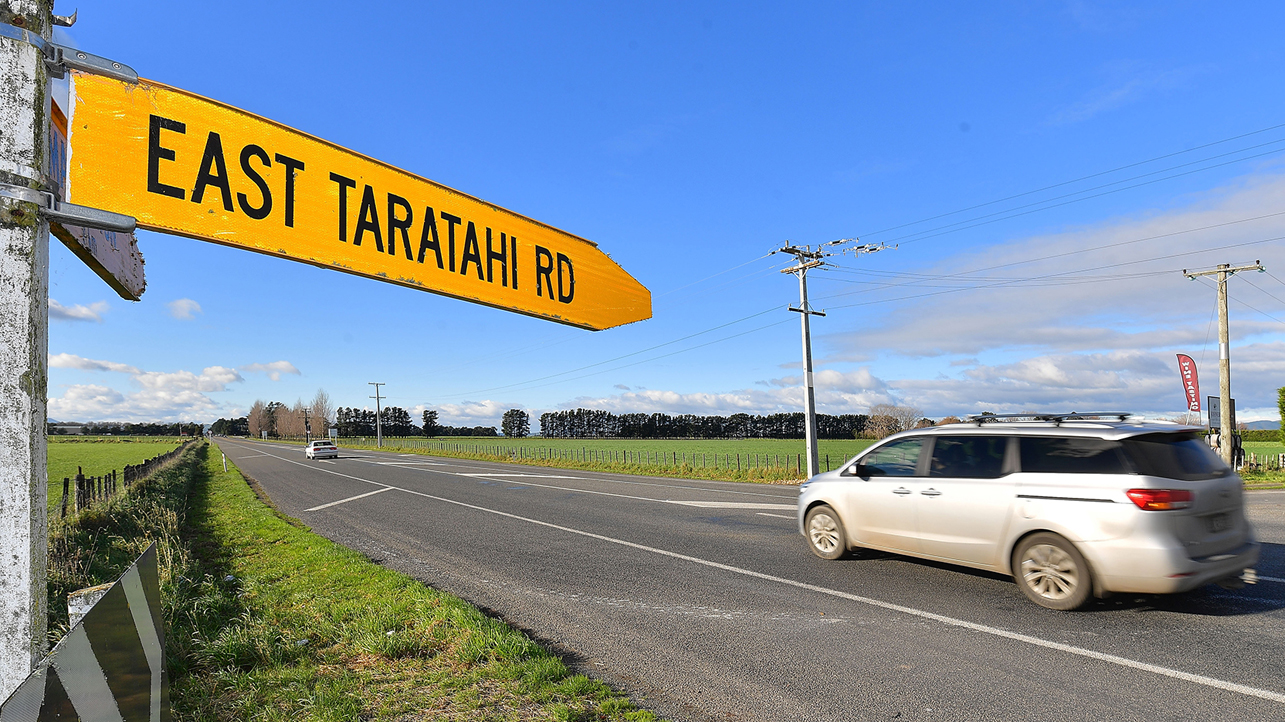 People mover driving along rural road with East Taratahi Rd sign pointing to the right.