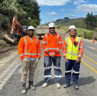 Three crew personnel posing at construction site of SH5