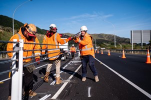 contractors in hi-vest installing median barriers on a highway road