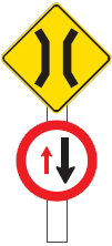 Two signs combined on one post, the top one is a permanent warning traffic sign on a yellow background showing a narrow bridge icon and the other is a regulatory sign with a red border showing one small red arrow going up and the other larger black arrow going down. This combo signage means give way to oncoming traffic on one-way or narrow bridge.